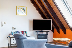 Une pièce avec une télévision, des livres, une chaise et une petite table.