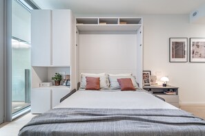 Ein modernes Schlafzimmer mit Bett, Nachttischen, einem Kleiderschrank und Bildern an der Wand.