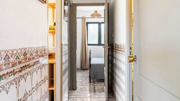 Un pasillo con paredes decoradas, suelo de baldosas y una puerta que da a una habitación.