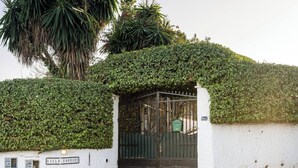 Une entrée fermée par un portail, avec un mur blanc et une plaque indiquant « Villa Torrenti ».