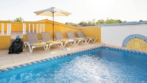 Une piscine avec des chaises longues et un parasol.