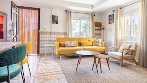Un salon avec un canapé, des fauteuils, une table et un tapis à motifs.