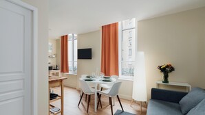 Ein kompakter Wohnraum mit Essbereich, einer Couch und einem an der Wand befestigten Fernseher.