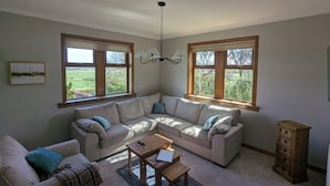 A living room with a sectional sofa, a coffee table, and a wooden cabinet. - Garden Cottage Near Edinburgh City Centre NEW (Edinburgh)