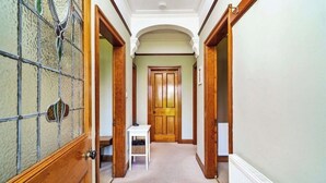 A hallway with a wooden door, a small table, and a radiator. - Garden Cottage Near Edinburgh City Centre NEW (Edinburgh)