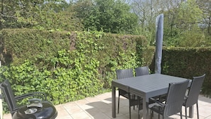 An outdoor patio with a table and chairs, surrounded by a hedge. - Residence close to beaches with terrace and garden (Saint-Coulomb)
