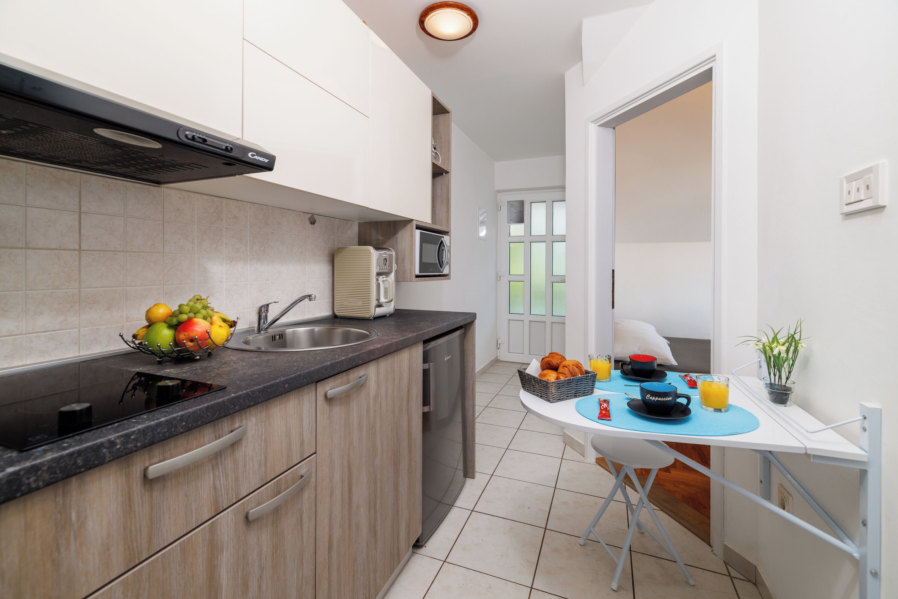 A modern kitchen with a built-in microwave, a sink, and a fruit bowl.