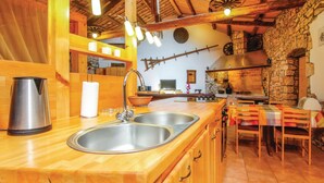 Eine Küche mit Holzausziehtisch, Edelstahlspüle und einer Steinwand.