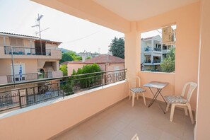 Ein Balkon mit Tisch und Stühlen, Blick auf benachbarte Gebäude und eine Flagge.