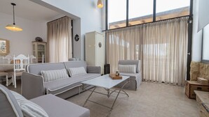 Un salon moderne comprenant un ensemble de canapés, une table basse et un coin repas avec une table et des chaises.