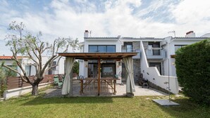 Une maison moderne à deux étages, dotée d’un patio couvert, d’un petit jardin et d’un garage apparent.