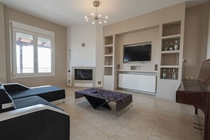 Ein Wohnzimmer mit einer Couch, einem Couchtisch, einem Fernseher und einem Kamin.