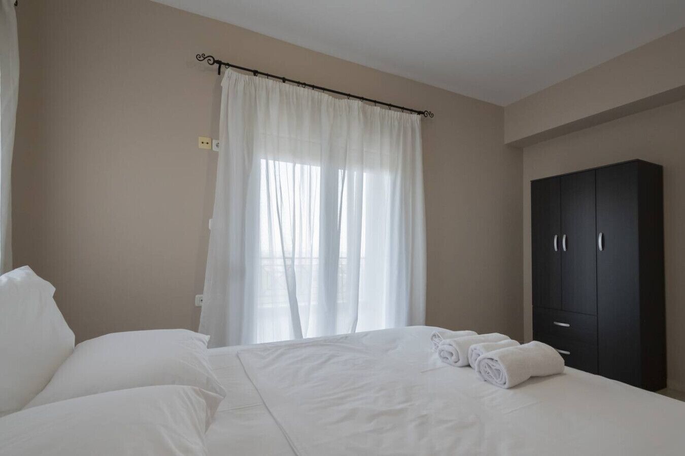 Una camera d'albergo con un letto, un armadio e una finestra con tende.