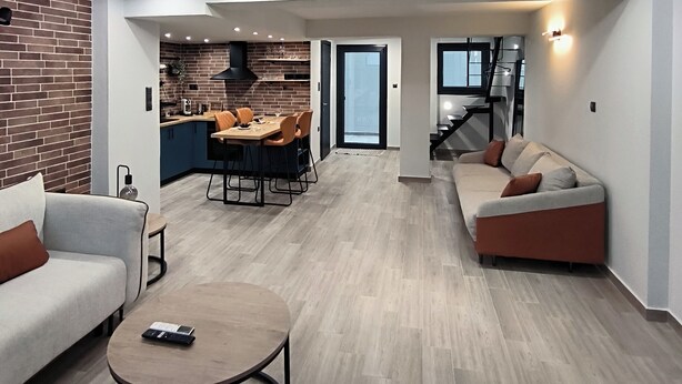 A modern interior with a dining area, sofa, and a staircase leading to a loft. - Zoe Loft ! (Kavala)