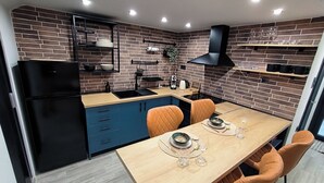 A modern kitchen with a brick wall, black appliances, and a dining area with orange chairs. - Zoe Loft ! (Kavala)