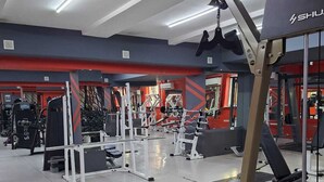 Una palestra con diverse attrezzature per esercizi, tra cui manubri, panche e macchinari per pesi.