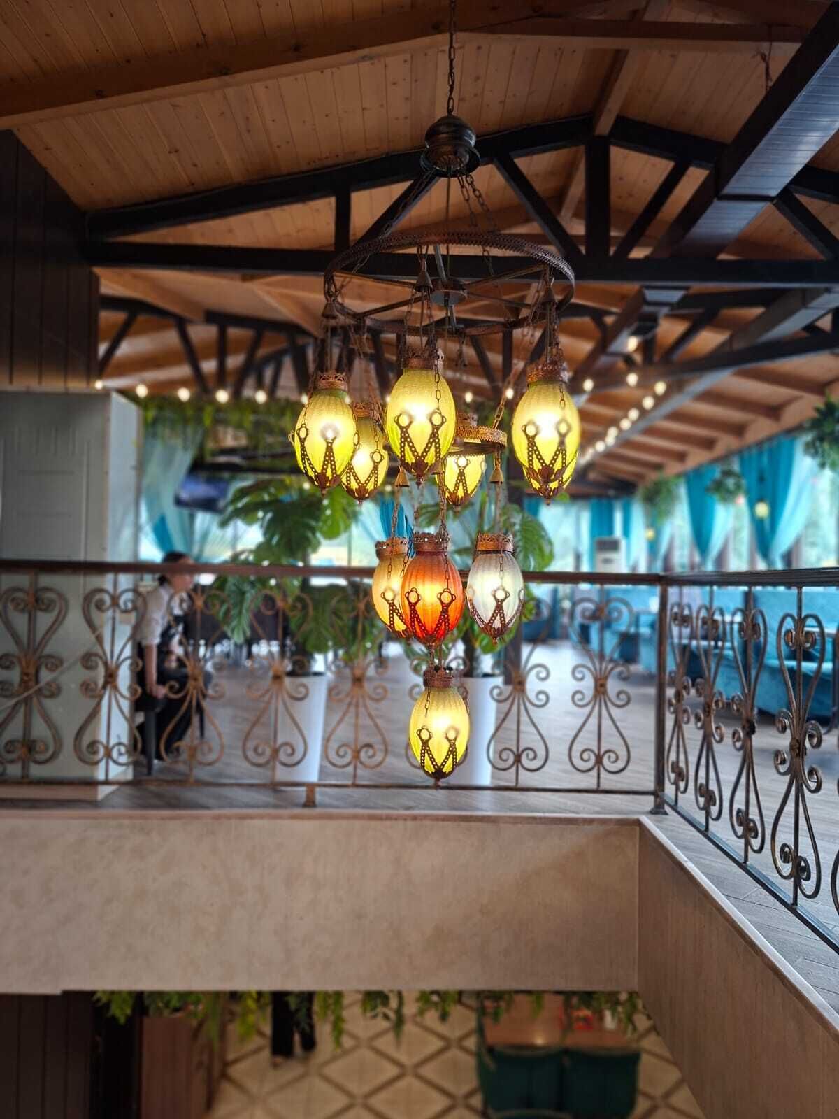 A hanging light fixture with multiple bulbs, a wooden ceiling, and a balcony railing.