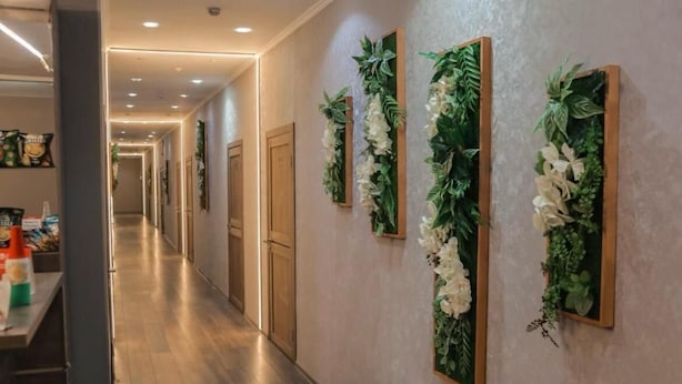 Un corridoio lungo con porte in legno e decorazioni murali verticali a motivi floreali.