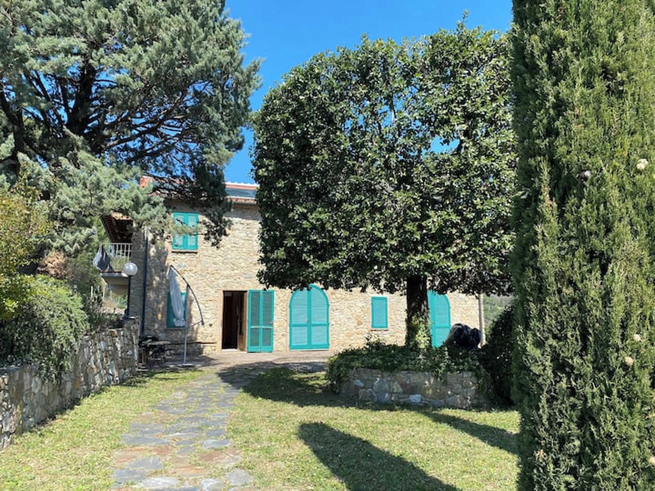 A stone building with a stone pathway leading to a wooden door, surrounded by greenery and trees.