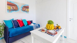 Een kamer met een blauwe bank, een witte tafel met eten, en een ananas als decoratie.