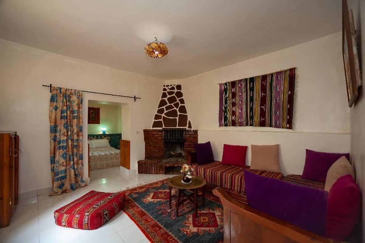 A living room with a fireplace, a sofa, a patterned rug, and a wall with a striped tapestry.