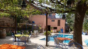 Eine Außenpatio mit Tischen, Stühlen, einem Pool und einem Gebäude im Hintergrund.