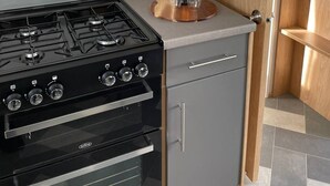 A kitchen with a gas stove, oven, and a wine bottle on the counter. - Yorkshire Lodge with Hot tub (york)