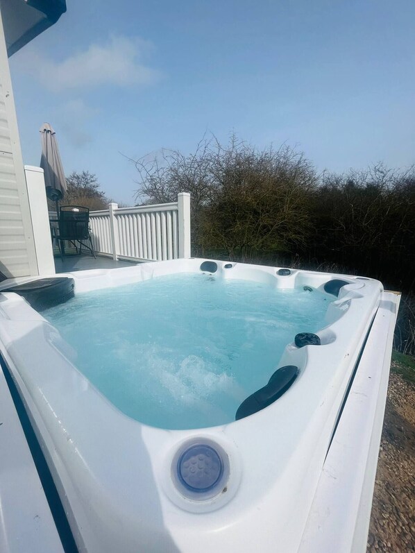 Un bain à remous avec une eau d’un bleu limpide, un panneau de commande et une structure extérieure blanche.