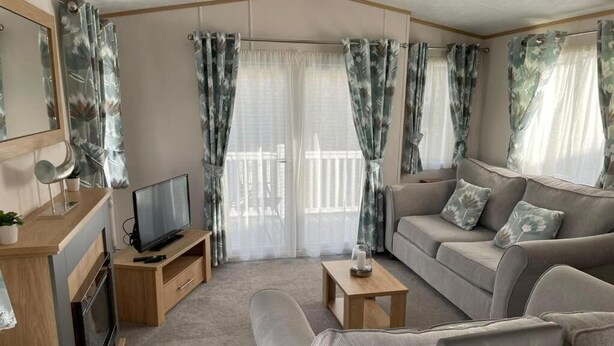 A modern living room with a sofa, TV, and a small table. - Yorkshire Lodge with Hot tub (york)