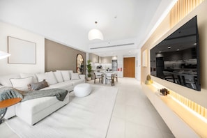 A modern living room with a sofa, coffee table, and dining area. - Free Housekeeping Visits During Your Stay - Stayshort - Modern 1BR Retreat in MJL Sleeps 4 (Dubai)