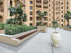 A multi-story residential building with balconies, a landscaped courtyard, and a large planter. - Free Housekeeping Visits During Your Stay - Stayshort - Modern 1BR Retreat in MJL Sleeps 4 (Dubai)