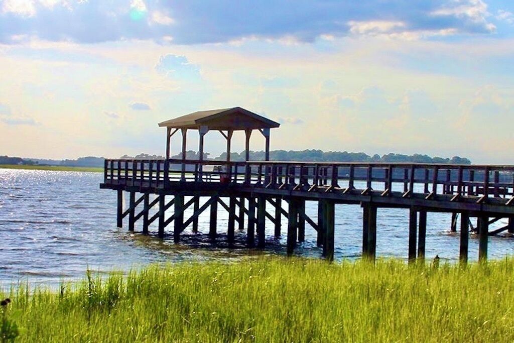 Une jetée en bois s’étendant sur une étendue d’eau, avec un pavillon couvert à son extrémité.
