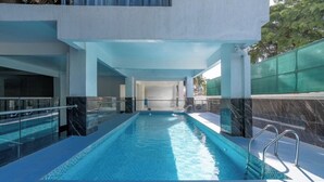 A swimming pool with glass railings, a clear blue water surface, and a modern architectural design. - The magical view condo kilimani (Nairobi)