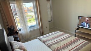 A hotel room with a bed, a TV, a desk with a chair, and a window with curtains. - Room-ensuite Room in 3 Bedroom Townhouse (Brampton)