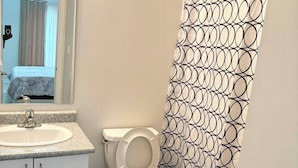 A bathroom with a toilet, sink, mirror, and shower curtain. - Room-ensuite Room in 3 Bedroom Townhouse (Brampton)