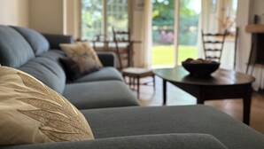 A modern living room with a sofa, a coffee table, and a dining area with chairs. - Casale del Sole in the hills of Trevignano: pool and nature 5 min. from the Lake! (Monterosi)