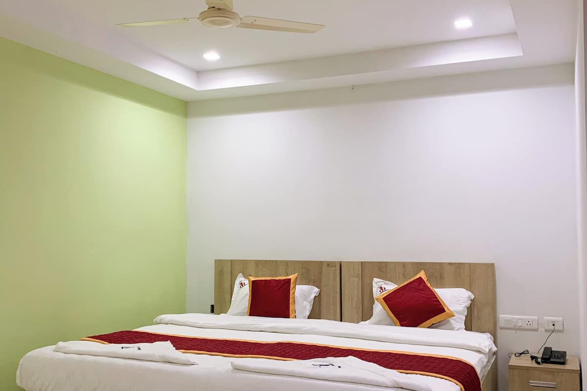 A bedroom with a wooden bed, a nightstand, a ceiling fan, and a wall socket.