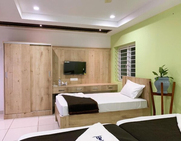 Un dormitorio con cama, televisor montado en la pared, armario y ventana con persianas.