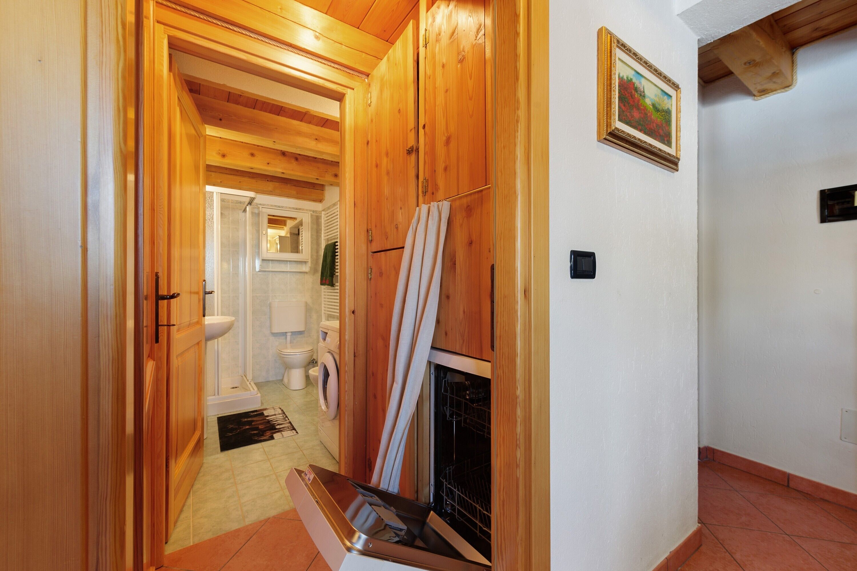 Pasillo interior de madera que conduce a un baño con lavadora y chimenea.