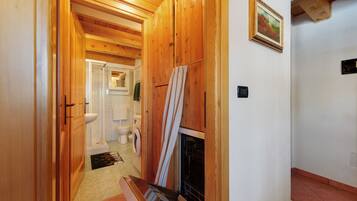 Pasillo interior de madera que conduce a un baño con lavadora y chimenea.