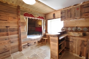Een houten interieur met een raam, een wastafel en kasten.