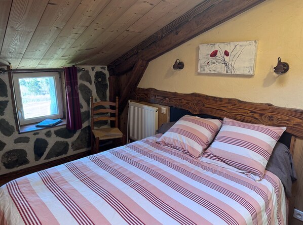 Ein Schlafzimmer mit einem Bett, einem Fenster, einem Sessel, einem Heizkörper und einem Bild an der Wand.