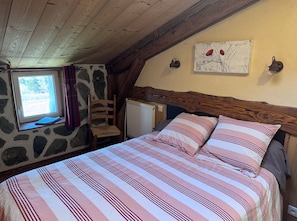 Ein Schlafzimmer mit einem Bett, einem Fenster, einem Sessel, einem Heizkörper und einem Bild an der Wand.