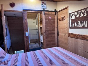 Ein Zimmer mit einem Bett, einer Holztür, einer Dusche und einer Wanddekoration.