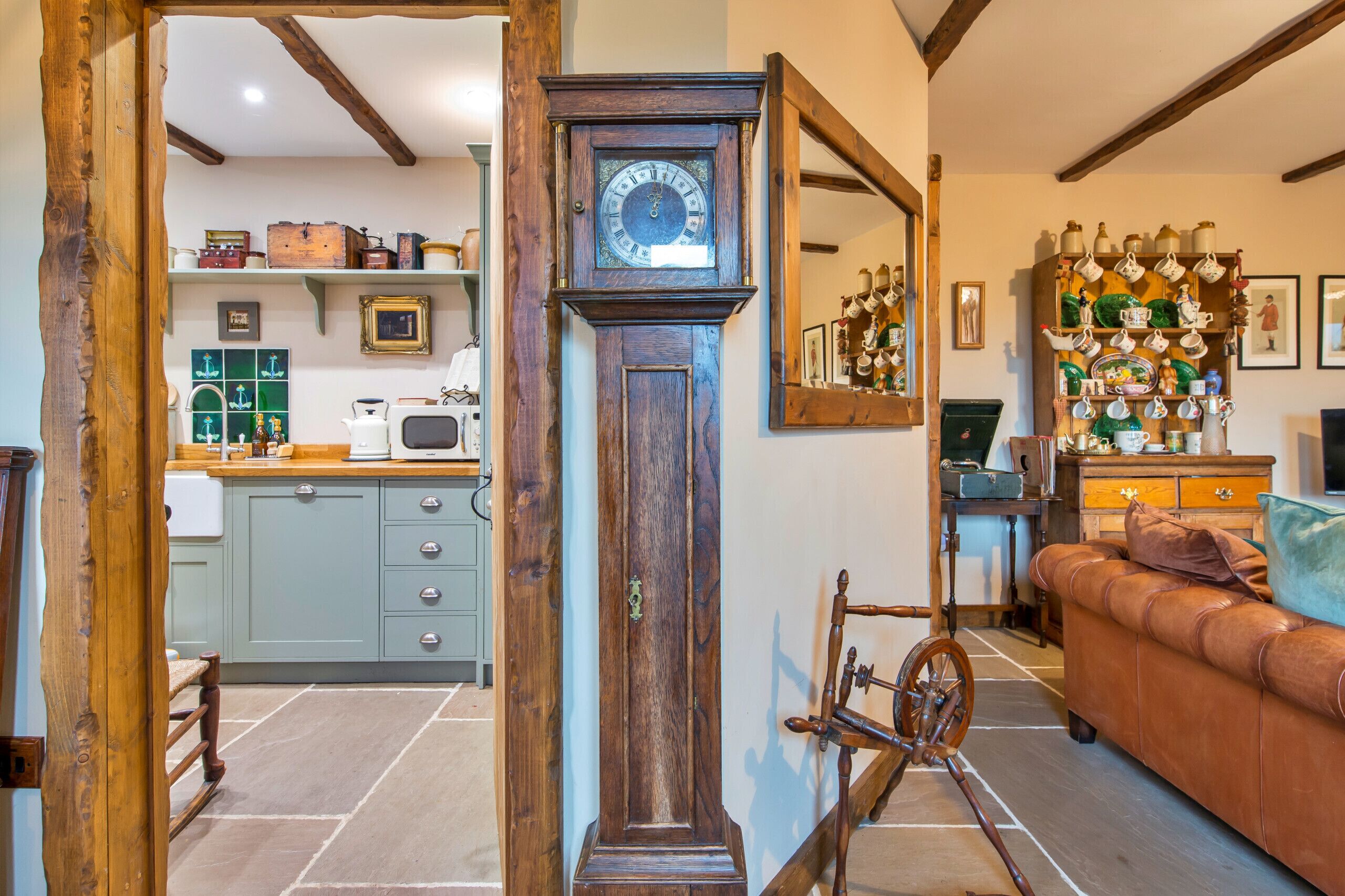 A traditional interior with a wooden grandfather clock, a vintage bicycle, and a cozy living area with a leather sofa.