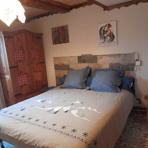 Een slaapkamer met een bed, een houten garderobe en een schilderij aan de muur.