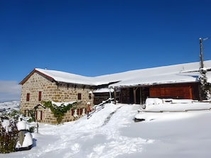 Een gebouw van steen met een houten uitbouw, omgeven door sneeuw.