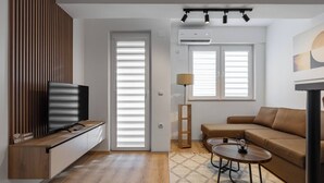 Un salon moderne avec un téléviseur, un canapé, une table basse et une lampe.
