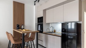 Une cuisine moderne avec une table en bois, des tabourets de bar, un réfrigérateur noir, un four à micro-ondes et un évier.