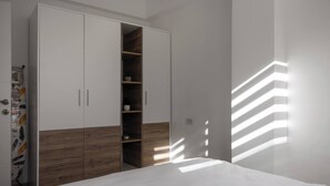 A bedroom with a bed, wardrobe, and built-in shelves. - Centrally Located Cozy D&O Apartment (Skopje)